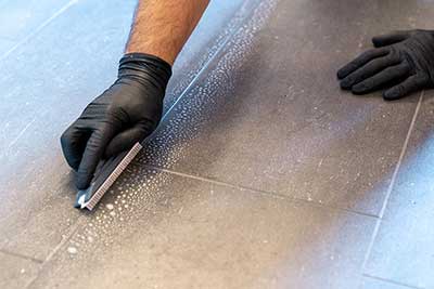 Hands regrouting bathroom using epoxy grout