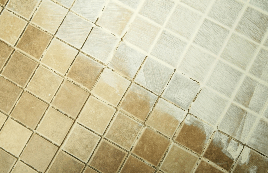 Close-up of shower floor tiles with worn and cracked grout lines