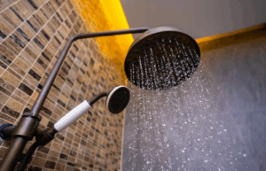 Close-up of a shower head with water flowing, showing potential leakage issues