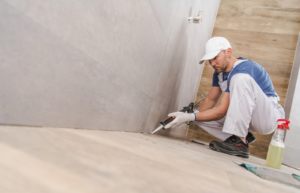 Tradesperson applying traditional sealant to a shower floor as part of waterproof sealing process
