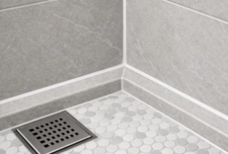 Close-up of a tiled shower corner with clean grout lines and floor drain after the regrouting service of SRC.