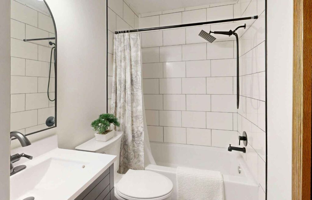 How Long Does Shower Waterproofing Last? 1 Bathroom with tiled shower over bathtub, highlighting shower waterproofing and protection against leaks in wet areas.